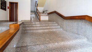 A staircase with granite steps and wooden handrails, leading to an elevator. - Elegant city center apartment close to all city attractions (Cagliari)