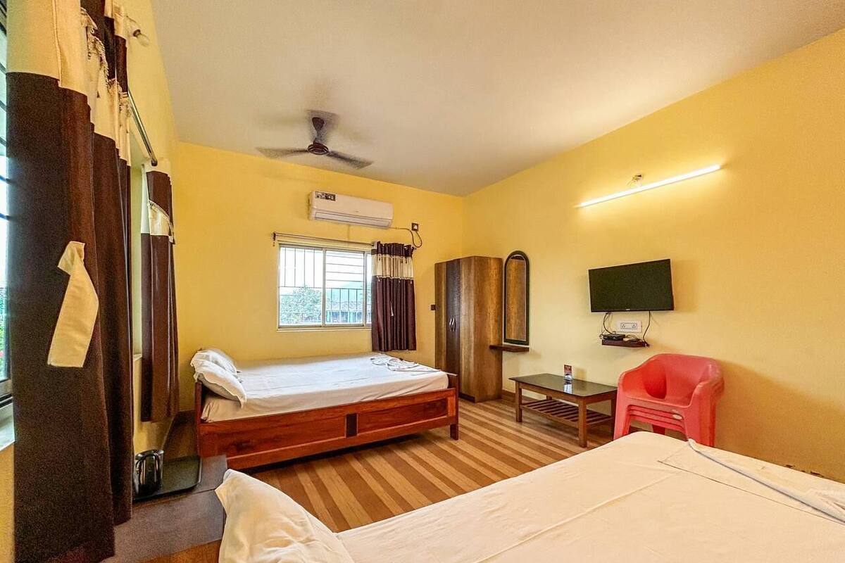 Quarto de hotel com cama, escrivaninha, cadeira, televisão e ar condicionado.
