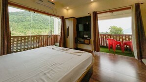 A bedroom with a bed, a TV, and a balcony with red chairs. - Allure De Baranti (Raghunathpur)