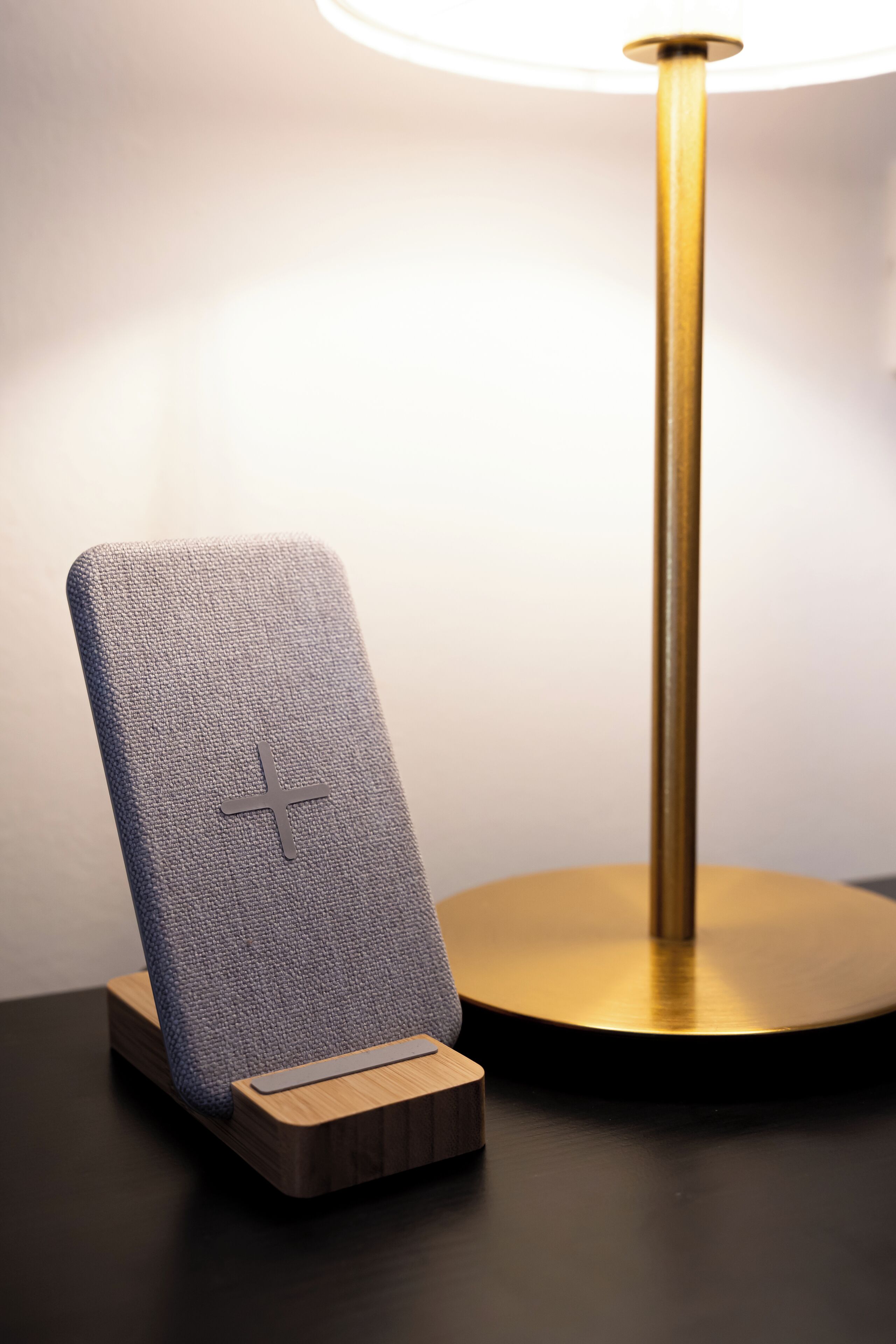 Eine moderne Lampe mit goldfarbenem Sockel und einem blauen, strukturierten Telefonständer.