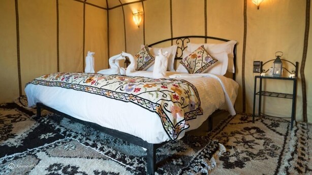 Een kamer met een bed, nachtkastje en wandlampen.