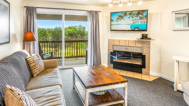 A living room with a sofa, a coffee table, a fireplace, and a TV mounted on the wall. - So Very Nice in Ocean Shores (Ocean Shores)