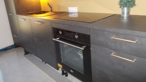 A kitchen with a built-in oven, a sink, and a small potted plant on the counter. - A Different Side of Provence (Jonquerettes)
