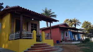 A two-story building with a yellow facade and a red roof. - Pousada Chalé Cantinho de Minas  (São João Batista do Glória)