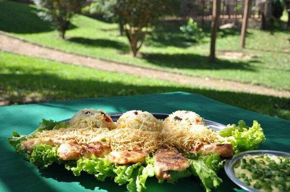 A meal of grilled chicken and rice on a green tablecloth outdoors.