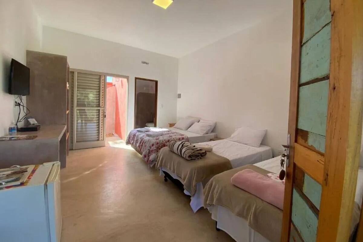 A bedroom with two beds, a television, and a desk.