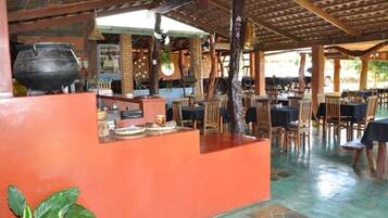 A restaurant with a rustic interior, featuring a large cooking pot, wooden tables, and a brick wall.