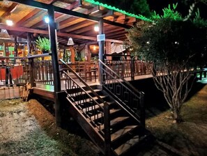 Ein überdachter Außenbereich mit einer Holztreppe, die zu einer Sitzgruppe führt.