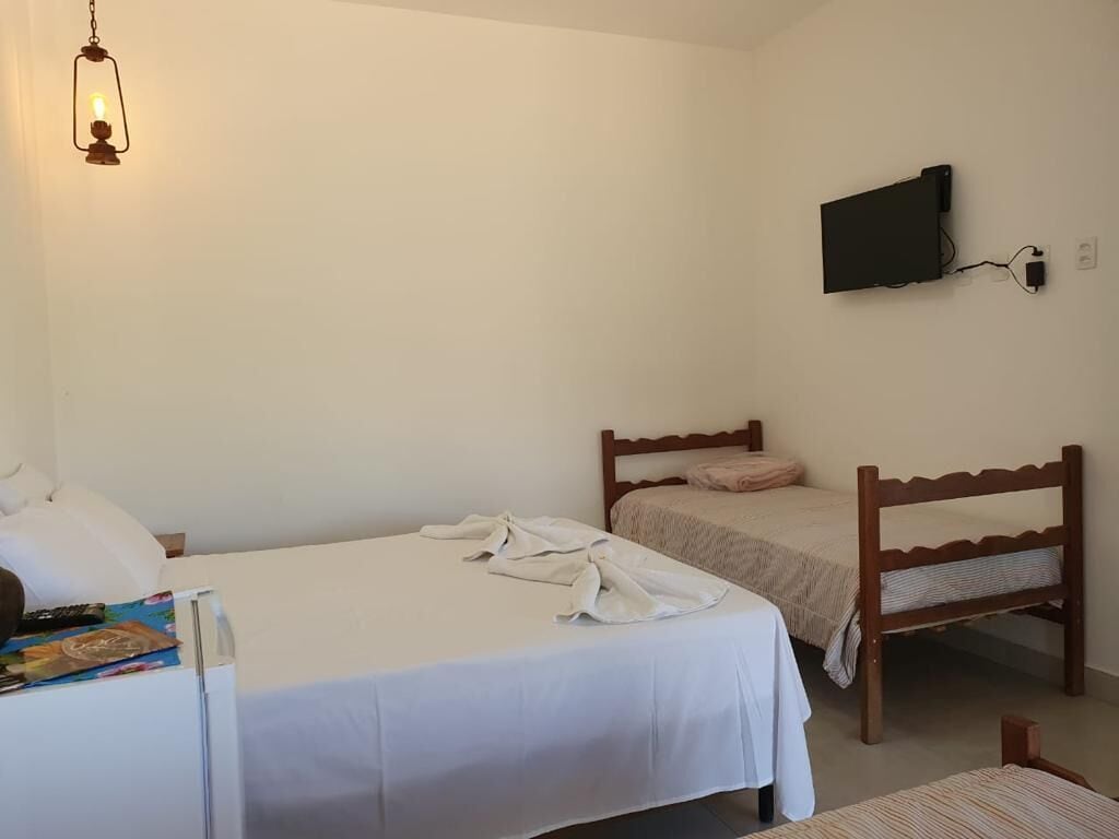 Un dormitorio con dos camas, un televisor montado en la pared y una mesita de noche con una lámpara.
