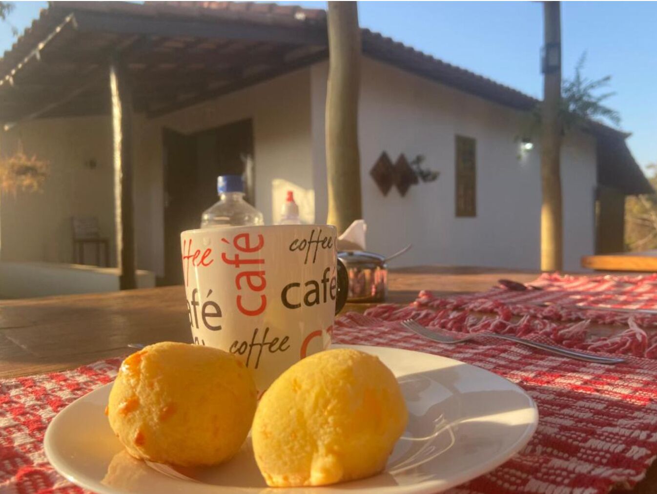 Une table avec une assiette de nourriture et une tasse de café devant un bâtiment.