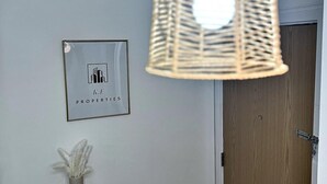 Ein Zimmer mit einer gewebten Pendelleuchte, einem gerahmten Bild an der Wand, einer Heizung und einer Tür.