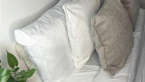 Ein weißes Sofa mit einer gemusterten Kissen, ein kleiner Holztisch und grüne Pflanzen.