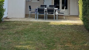 A two-story house with a balcony, a patio with a table and chairs, and a small garden area. - Villa with communal pool in St palais sur mer (Saint-Palais-sur-Mer)