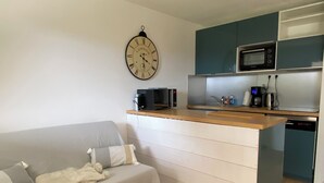 A compact living space with a kitchenette, a sofa, a coffee machine, and a clock on the wall. - Villa with communal pool in St palais sur mer (Saint-Palais-sur-Mer)