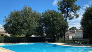 A rectangular swimming pool with a tiled deck, surrounded by a fence and trees. - Villa with communal pool in St palais sur mer (Saint-Palais-sur-Mer)