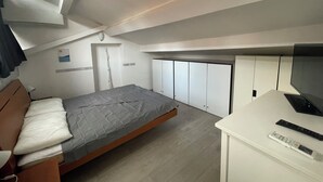 Une chambre à coucher de taille réduite, comprenant un lit, un petit bureau et une armoire.