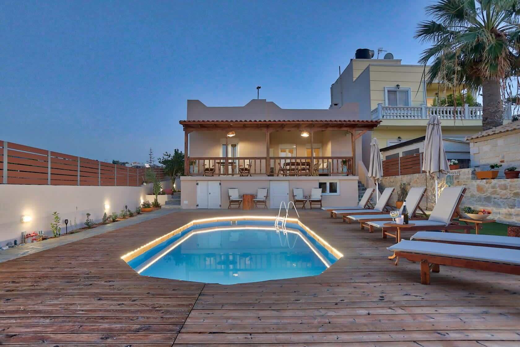 A swimming pool with a wooden deck, lounge chairs, and a bar area with seating.
