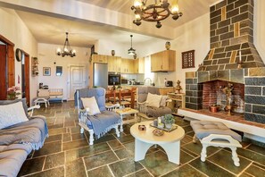 A spacious living area with a fireplace, a dining area, and a kitchen. - Anacosta Villa w/ Private Pool, Cretan Seaside Gem (Anisaras, Hersonisos)