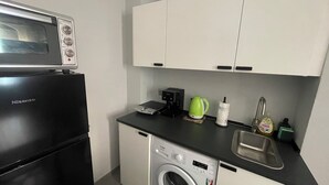 A compact kitchen with a microwave, coffee maker, kettle, and washing machine. - Pretty Flat Alassio Moglio (Moglio)