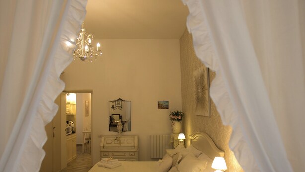 A bedroom with a bed, nightstands, a chandelier, and a mirror.