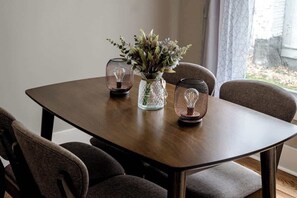 A dining table with four chairs, a vase with flowers, and two decorative light fixtures.