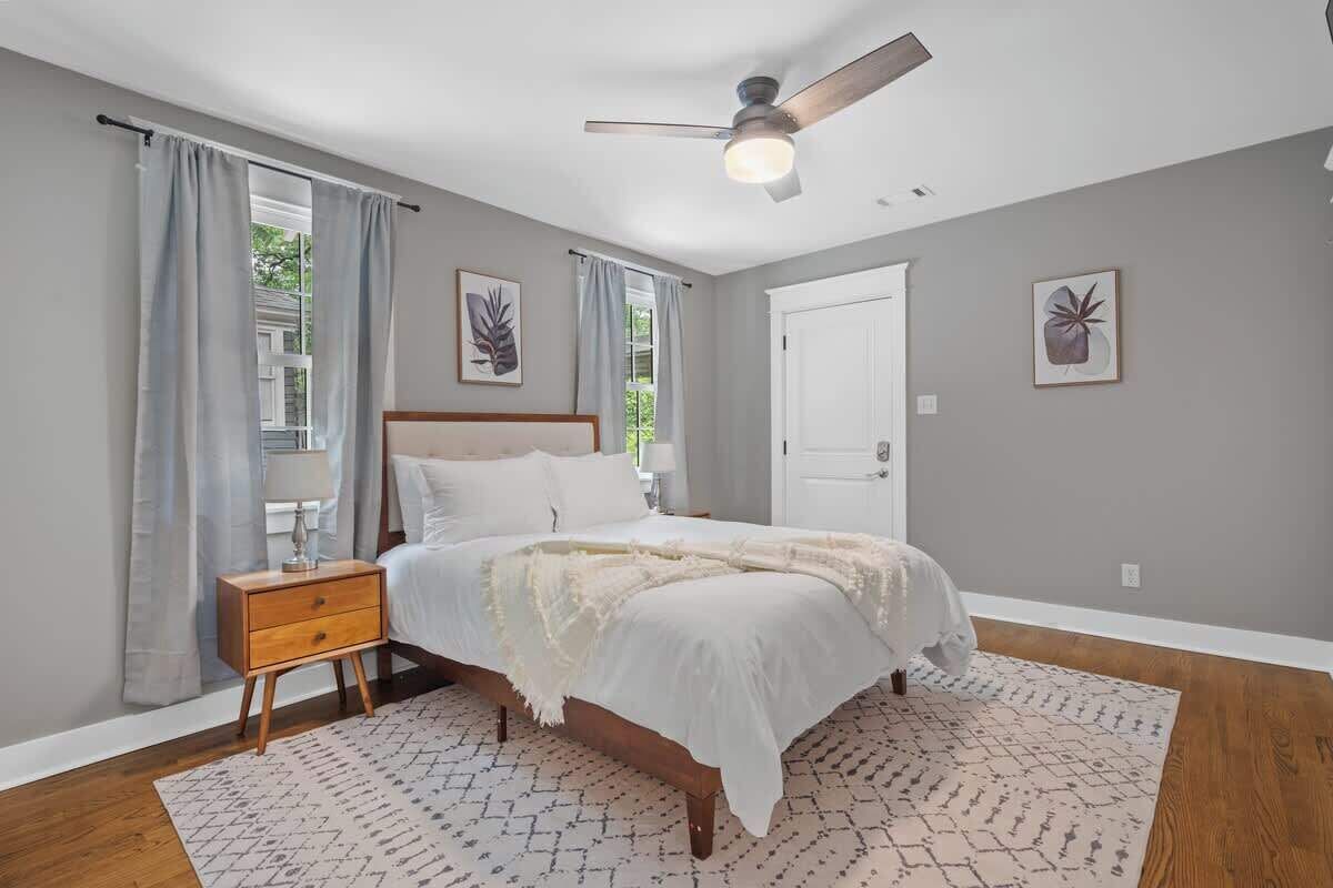 Ein Schlafzimmer mit Bett, Nachttisch, Deckenventilator und zwei gerahmten Bildern an der Wand.