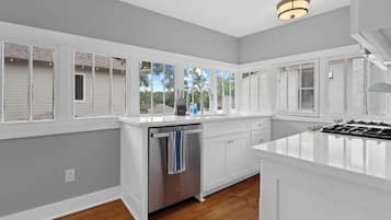 A kitchen with white cabinetry, a stainless steel dishwasher, and a gas stove.