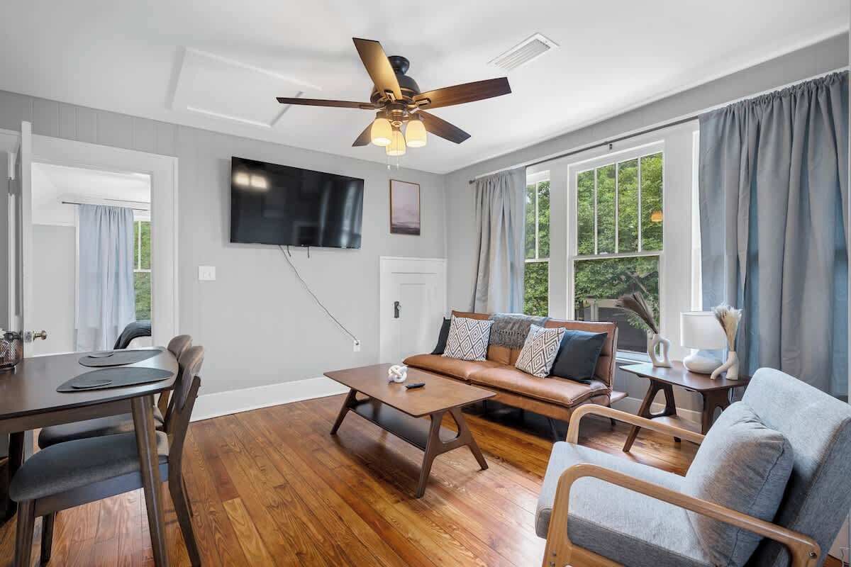 A living room with a sofa, coffee table, TV, and a ceiling fan.