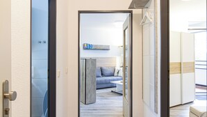 A modern hallway with a grey sofa, a white coffee table, and a wooden floor. - Moderne Ferienwohnung Sauerland am Bikerpark (Winterberg)