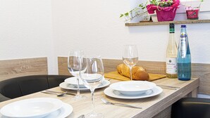 A dining table set with plates, glasses, and cutlery, a loaf of bread, and bottles of water and wine. - Moderne Ferienwohnung Sauerland am Bikerpark (Winterberg)