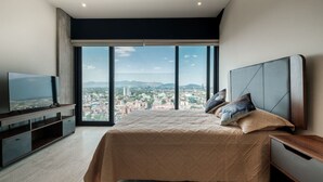 A bedroom with a large bed, a TV, and a city view. - Casa Bee walking distance to Reforma (Ciudad de México)