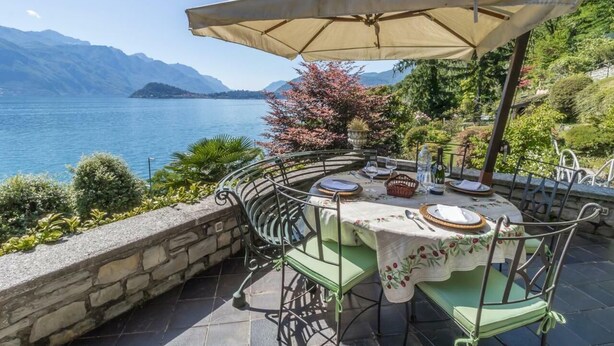 Une table dressée à l’extérieur, avec vue sur un lac et des montagnes.