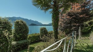 Une vue pittoresque d’un lac, avec des montagnes en arrière-plan, entouré d’une végétation luxuriante et agrémenté d’un banc en bois.
