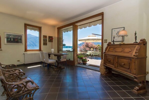 A room with a view of mountains, a dining area with chairs and a table, and a wooden cabinet.