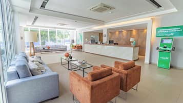Un moderno vestíbulo de hotel con una recepción, zona de estar y quiosco de registro.