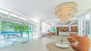 Un moderno vestíbulo de hotel con amplios ventanales, un mostrador de recepción y zonas de estar.