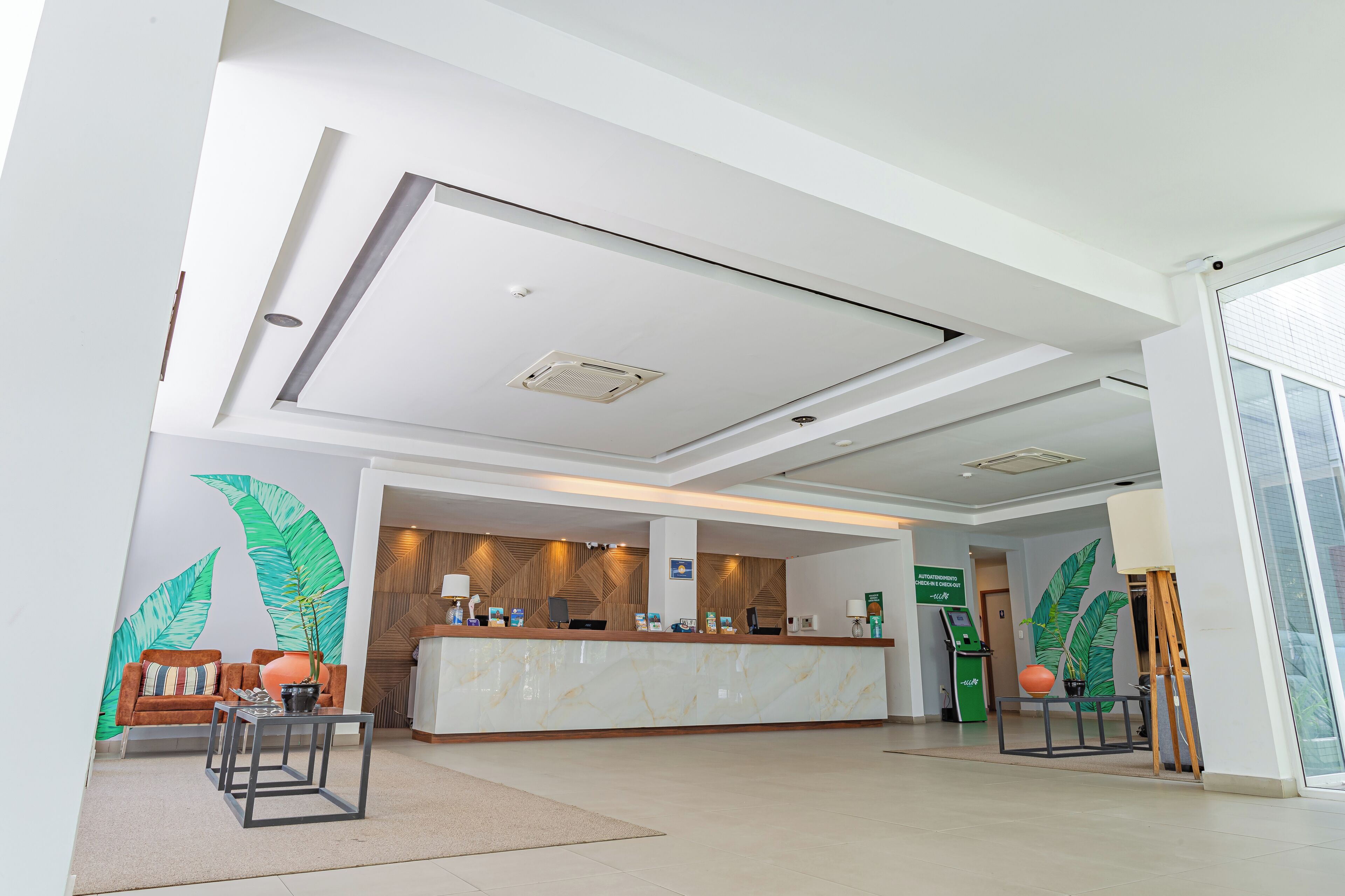Un área de recepción moderna con una barra de mármol, un mostrador de madera y un gran mural en la pared.