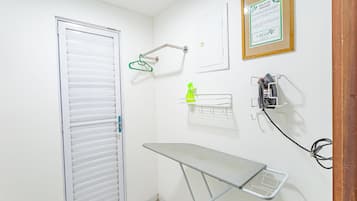 Une petite pièce propre, avec une porte blanche, un cintre vert, un panneau encadré et une prise électrique fixée au mur.