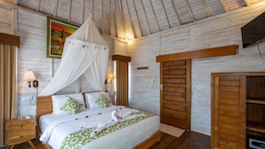 A bedroom with a canopy bed, wooden walls, a painting, and a wardrobe. - Island Retreat Cottage (Lembongan Island)