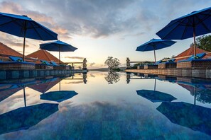 A serene pool area with clear reflections, lounge chairs, and umbrellas. - Island Retreat Cottage (Lembongan Island)