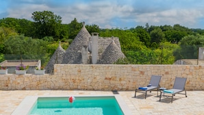 A swimming pool with stone walls and a view of greenery.