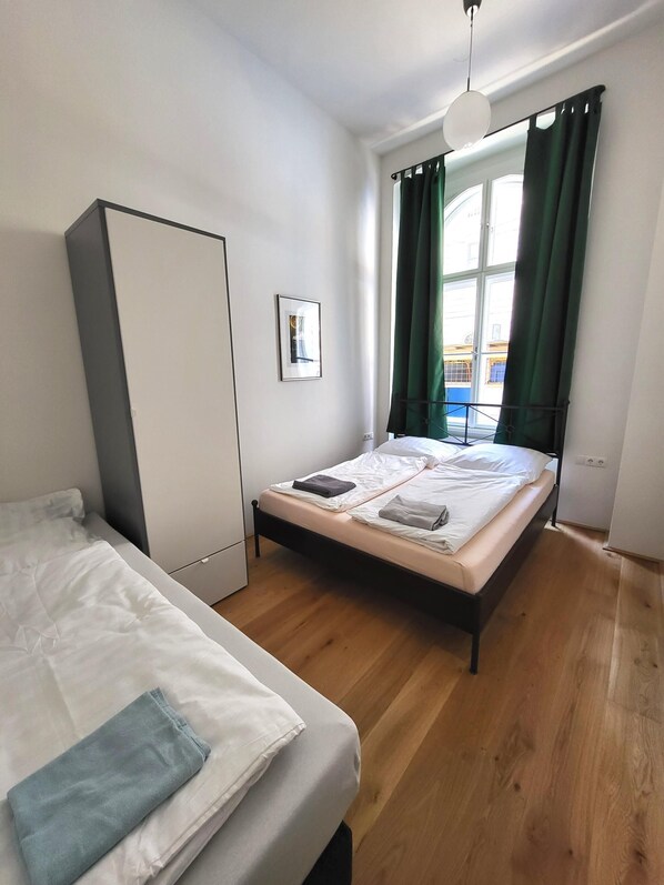 A bedroom with a bed, a wardrobe, a picture on the wall, and a window with curtains.