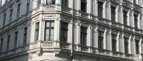 A large, historic building with a classical architectural style, featuring multiple windows and a prominent corner entrance.