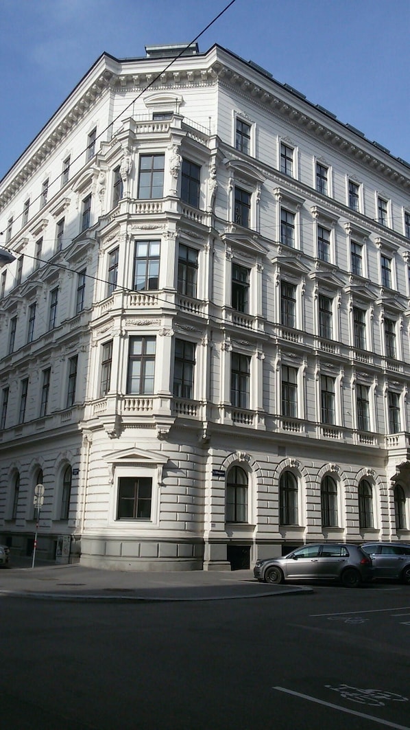 A large, historic building with a classical architectural style, featuring multiple windows and a prominent corner entrance.