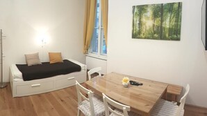A small, bright room with a bed, a dining table, and a painting on the wall. - Central family Apartment A16 with AC (Vienna)