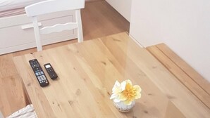 A small dining area with a wooden table, a flower vase, and a remote control on the table. - Central family Apartment A16 with AC (Vienna)