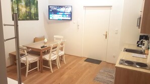 A compact kitchen with a dining area, a TV mounted on the wall, and a door leading to another room. - Central family Apartment A16 with AC (Vienna)