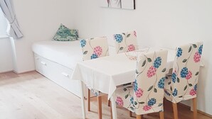Ein Essbereich mit einem weißen Tisch und Stühlen mit Blumenmuster, einem weißen Sofa und einem Bild an der Wand.
