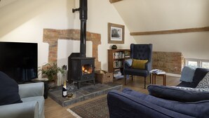 Una sala de estar acogedora con chimenea, estantería y asientos cómodos.