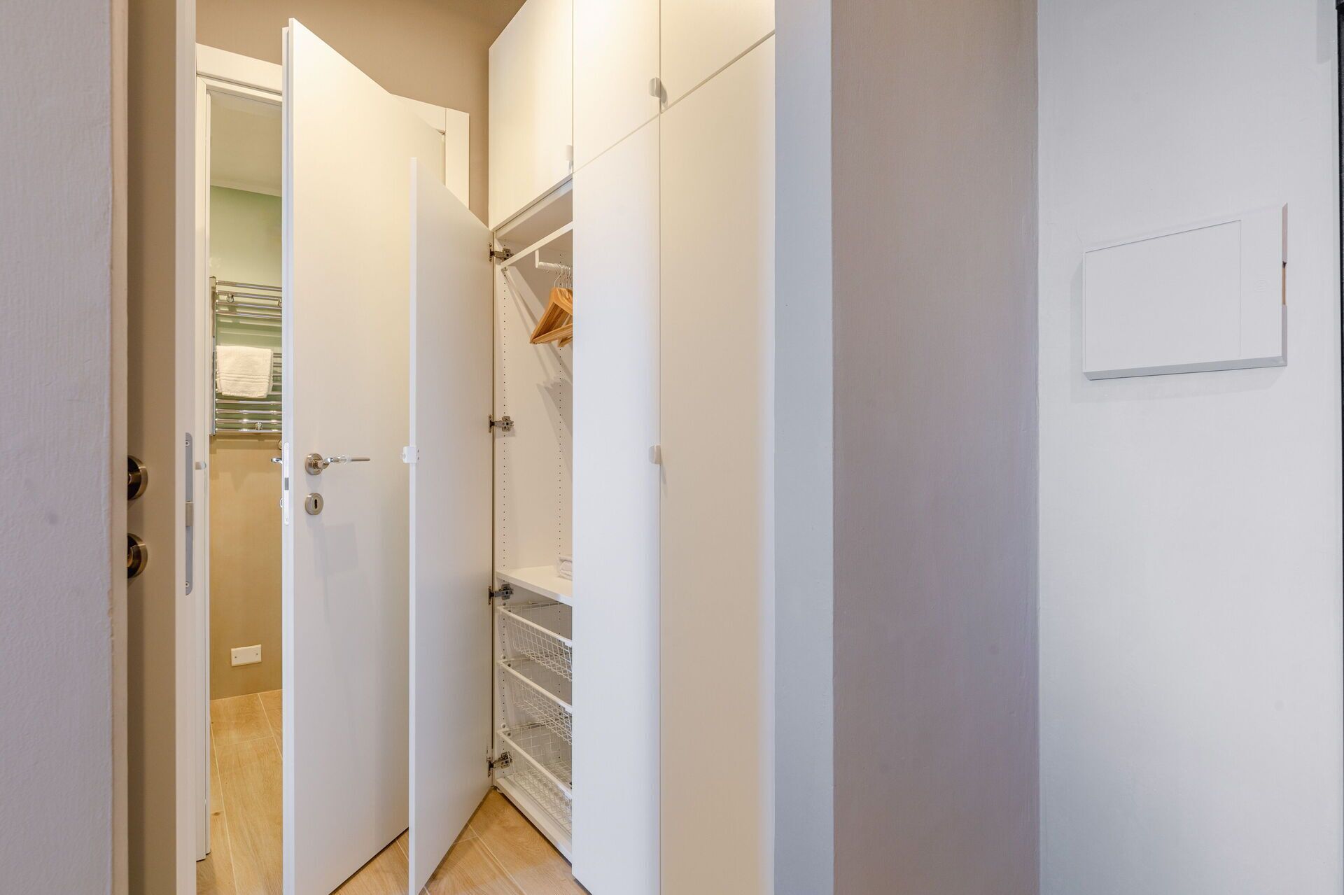 Un couloir étroit aux murs blancs, avec une porte donnant sur une salle de bain.